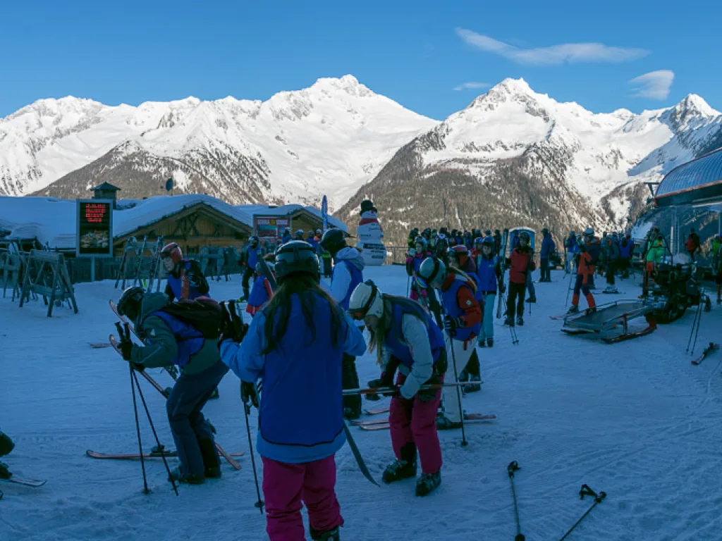 Skifahrende an der Bergstation vor dem Panorama.